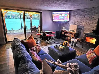 a living room with a blue couch and a tv at Lakefront Hot Tub Canoes Game Room Wood FP in Gouldsboro