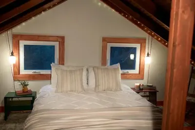 a bedroom with a white bed with two windows at Woodside Cabin in Delaware Water Gap in Dingmans Ferry