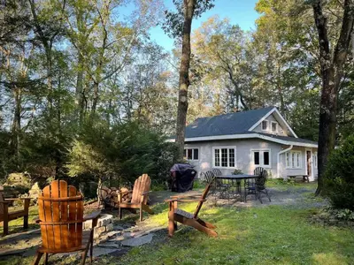 a white house with a table and chairs in the yard at Woodside Cabin in Delaware Water Gap in Dingmans Ferry