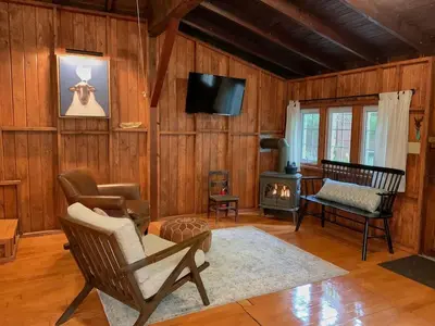 a living room with a chair and a fireplace at Woodside Cabin in Delaware Water Gap in Dingmans Ferry