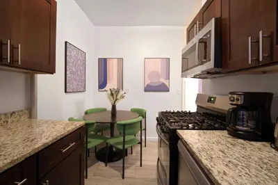 a kitchen with a stove and a table with green chairs at Bright 3BD Unit Close to Columbia University & Central Park in New York