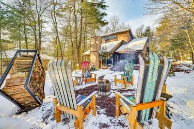 a group of chairs in the snow in front of a house at Lake Naomi Luxury Home with Stream Pool and Fire Pit in Pocono Pines
