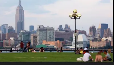 a group of people sitting in a park with a city skyline at New Cozy Must Have Stay! 10 minutes to NYC in Hoboken