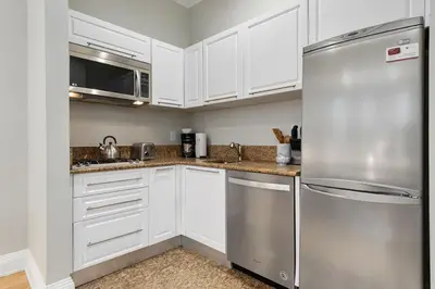 a kitchen with white cabinets and a stainless steel refrigerator at Synergy Madison in New York