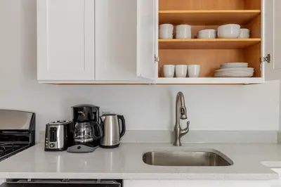 a kitchen with white cabinets and a sink and a counter top at Blueground Alphabet City washer nr Tompkins Square Park NYC-2161 in New York