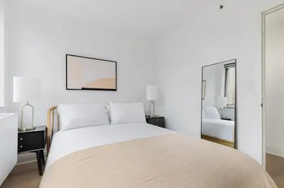 a white bedroom with a bed and a chair at Blueground Kips Bay rooftop nr NYC Skyline NYC-2158 in New York