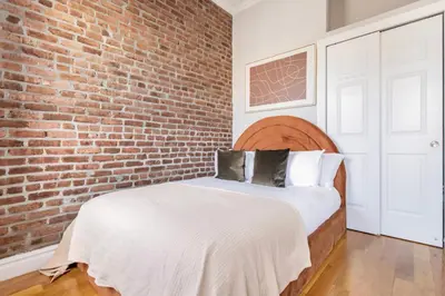 a bedroom with a brick wall and a bed at Blueground Nolita view nr Washington Square NYC-2051 in New York