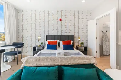 a bedroom with a large bed with blue and orange pillows at Lux Studio Apt - Rooftop - 5 mins to The Fillmore in Philadelphia