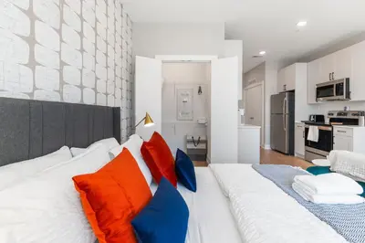 a large white bed with colorful pillows in a room at Lux Studio Apt - Rooftop - 5 mins to The Fillmore in Philadelphia