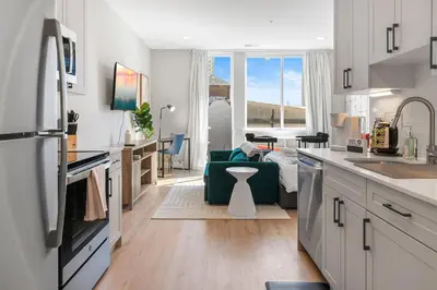 a kitchen with white cabinets and a green couch at Lux Studio Apt - Rooftop - 5 mins to The Fillmore in Philadelphia