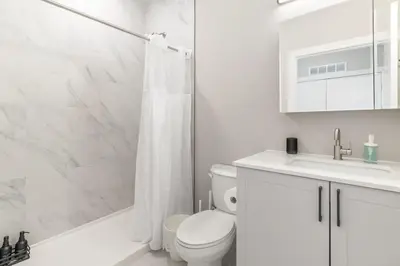 a white bathroom with a toilet and a sink at Lux Studio Apt - Rooftop - 5 mins to The Fillmore in Philadelphia