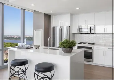 a kitchen with white cabinets and a counter with stools at Everlasting Reality in Fort Lee