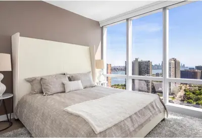 a bedroom with a large bed with a large window at Everlasting Reality in Fort Lee