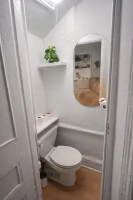 a white bathroom with a toilet and a mirror at Cozy Little Italy Retreat Steps from SoHo in New York
