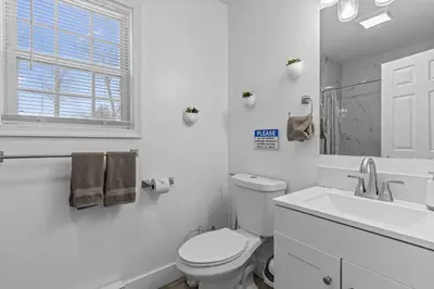 a white bathroom with a toilet and a sink at Evergreen Villa Poconos - Hot Tub, Fire Pit, Close to Kalahari, Great Wolf Lodge and Camelback in Tobyhanna