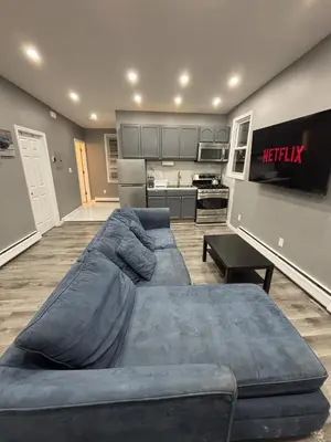 a living room with a large couch and a kitchen at The loft 2 bedroom apartment in Newark