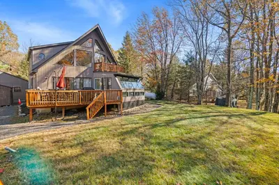 a large house with a deck and a yard at Lakefront with Beach Game Room Fire-pit and More in Blakeslee