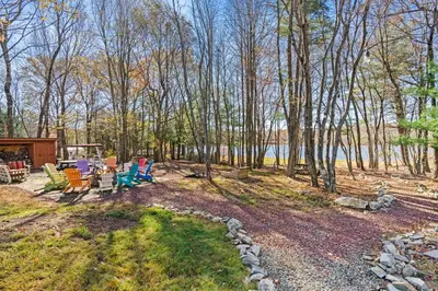 a group of chairs sitting on the grass near the water at Lakefront with Beach Game Room Fire-pit and More in Blakeslee
