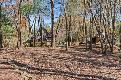 a yard with trees and a house in the background at Lakefront with Beach Game Room Fire-pit and More in Blakeslee