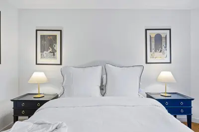 a bedroom with a white bed with two lamps on tables at Chelsea 1BR in Shared Apt with Laundry and Rooftop in New York