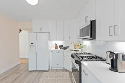a kitchen with white cabinets and a white refrigerator at Charming Entire Home,18m to Manhattan, Home Theater in Carlstadt