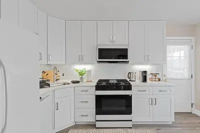 a white kitchen with white cabinets and a stove top oven at Charming Entire Home,18m to Manhattan, Home Theater in Carlstadt