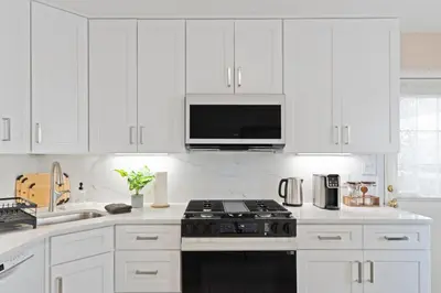 a white kitchen with a stove and a microwave at Charming Entire Home,18m to Manhattan, Home Theater in Carlstadt