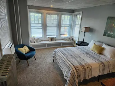 a bedroom with a bed and a chair and windows at Waterfront Getaway in Historic Bristol in Bristol