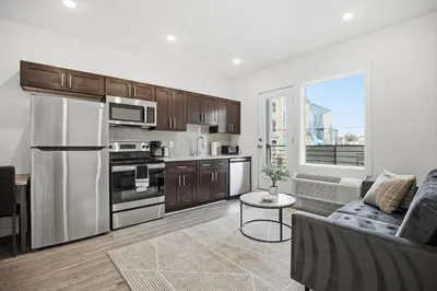 a kitchen with stainless steel appliances and a living room at 1BR1BA apartment in the Fairmount Square building in Philadelphia