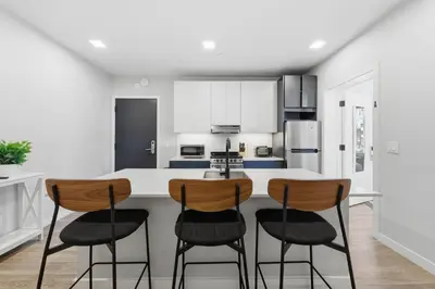 a kitchen with a white counter and three bar stools at Modern 2BR, 1BA Apartment in Great Location in Philadelphia