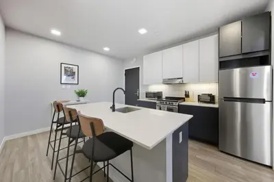 a kitchen with white cabinets and a kitchen island with bar stools at Modern 2BR, 1BA Apartment in Great Location in Philadelphia