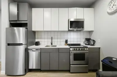 a kitchen with white cabinets and a stainless steel refrigerator at Cozy 1BR Apartment in Philly Prime Location in Philadelphia