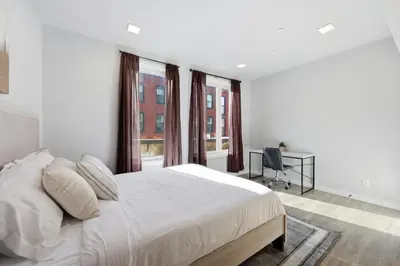a white bedroom with a bed and a desk and windows at Sleek 1BR apartment in Philly in Philadelphia