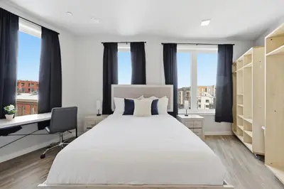 a bedroom with a large bed with a desk and windows at Bright Modern 2BR Apartment in Prime Location in Philadelphia