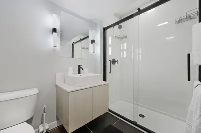 a white bathroom with a sink and a shower at Bright Modern 2BR Apartment in Prime Location in Philadelphia