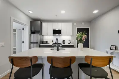 a kitchen with a white counter and four chairs at Bright Modern 2BR Apartment in Prime Location in Philadelphia