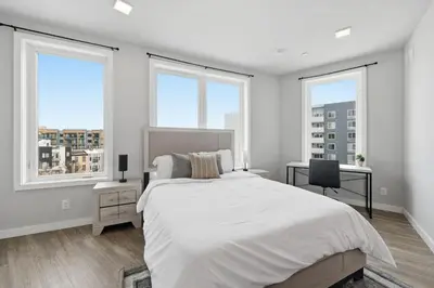a white bedroom with windows and a bed and a desk at Contemporary 2BR Apartment Near Everything in Philadelphia