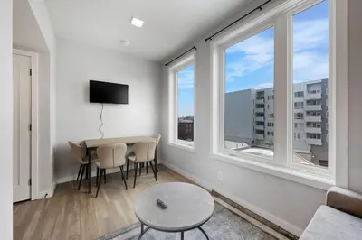 a living room with a table and two windows at Contemporary 2BR Apartment Near Everything in Philadelphia