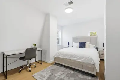 a white bedroom with a desk and a bed at A Modern 1BR Oasis in Carriage House in Philadelphia