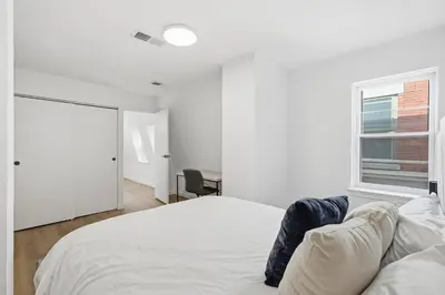 a white bedroom with a bed and a window at A Modern 1BR Oasis in Carriage House in Philadelphia