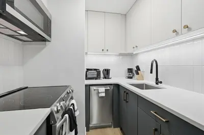a white kitchen with a sink and a dishwasher at A Modern 1BR Oasis in Carriage House in Philadelphia