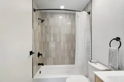a white bathroom with a tub and a toilet at A Modern 1BR Oasis in Carriage House in Philadelphia