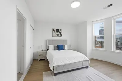 a white bedroom with a bed and two windows at Carriage House Sleek 1BR Apartment in Philadelphia