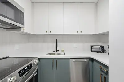 a kitchen with white cabinets and a sink at Carriage House Sleek 1BR Apartment in Philadelphia