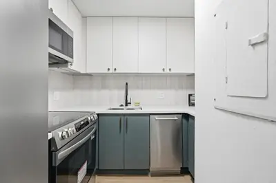 a kitchen with white cabinets and a sink at Carriage House Sleek 1BR Apartment in Philadelphia