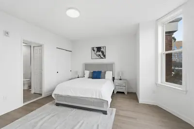 a white bedroom with a bed and a window at Carriage House Sleek 1BR Apartment in Philadelphia