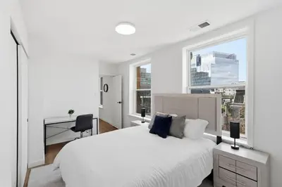 a white bedroom with a large bed and a desk at Carriage House Stylish 1BR Retreat in Philadelphia