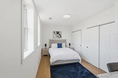a white bedroom with a bed and a blue rug at Cozy, Modern Living at Carriage House in Philadelphia