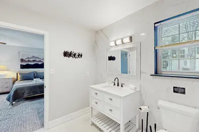a white bathroom with a sink and a bed at The Nest in Long Pond