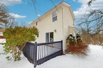 a white house with a fence in the snow at The Nest in Long Pond
